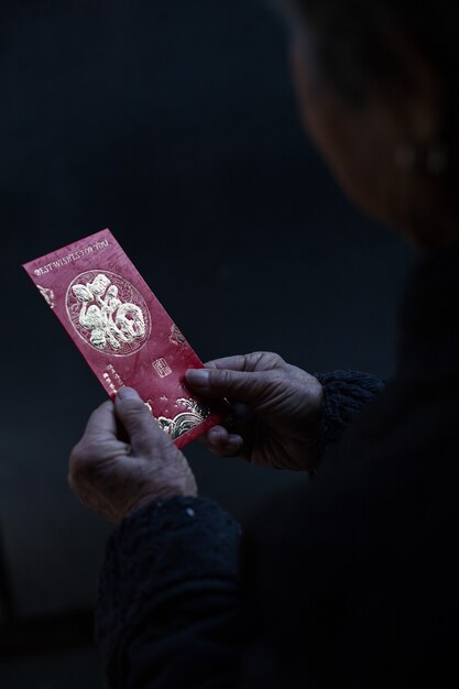 Femme chinoise tenant une enveloppe rouge traditionnelle avec des voeux de nouvel an chinois