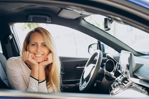 Femme choisissant une voiture dans une salle d'exposition automobile