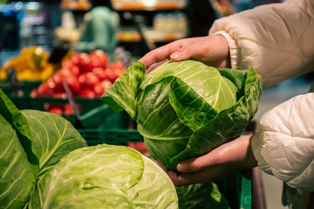 Une Femme Choisit Le Chou Dans Un Gros Plan D'épicerie