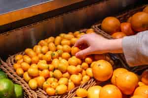 Photo gratuite une femme choisit le kumquat en gros plan dans une épicerie