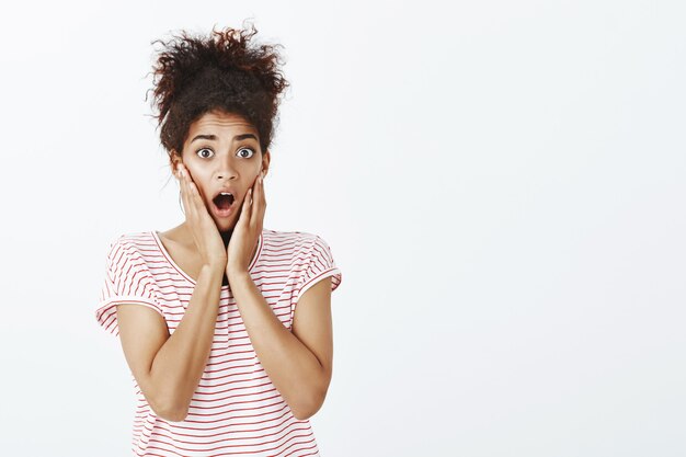 femme choquée avec une coiffure afro qui pose en studio