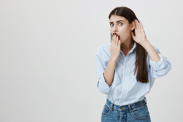 Femme choquée écoute, couvre la bouche