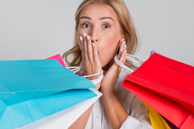 Femme choquée posant avec de nombreux sacs à provisions colorés