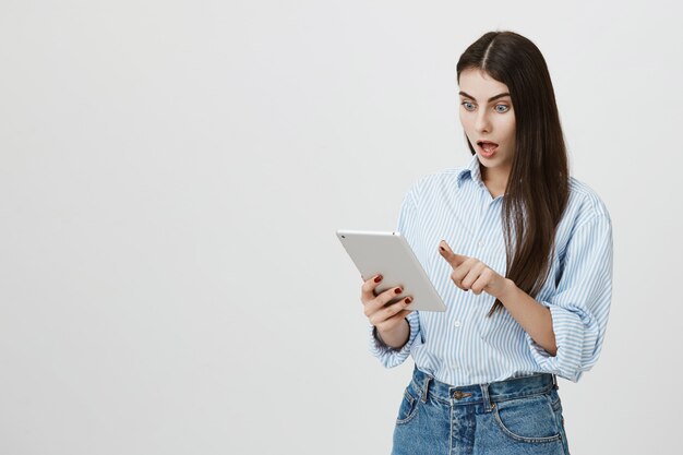 Femme choquée regardant excité à l'écran de la tablette numérique