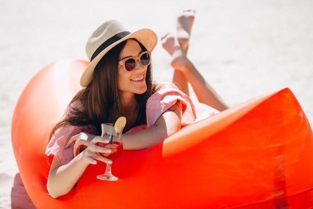 Femme avec coctail au chapeau à la plage