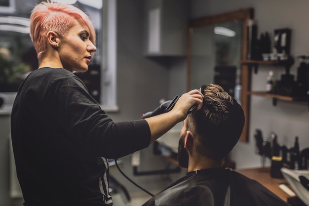 Femme coiffeuse séchant la tête du client