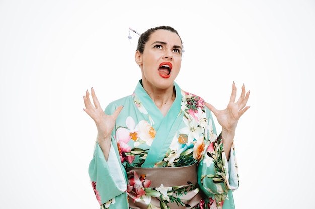 Femme en colère en kimono japonais traditionnel levant les mains en hurlant sur blanc