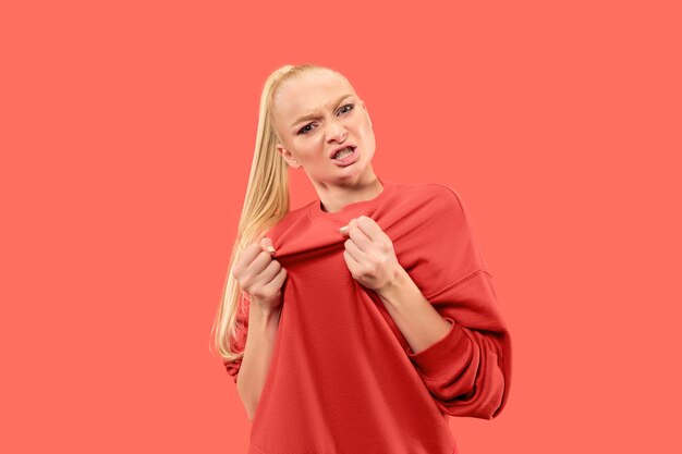 Femme en colère regardant la caméra. Femme d'affaires agressive debout isolée sur fond de studio de corail à la mode. Portrait de femme demi-longueur. Émotions humaines, concept d'expression faciale