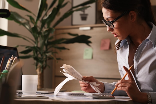 Photo gratuite femme comptable calculant les factures d'impôt tout en travaillant sur les finances au bureau