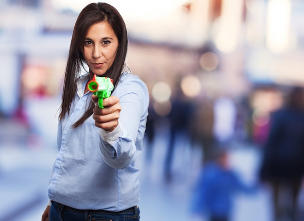 femme concentré tenant une arme de poing en plastique