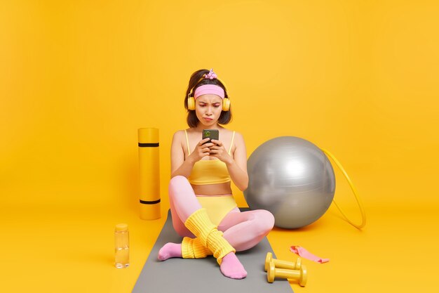 une femme concentrée sur l'affichage du smartphone utilise un équipement de sport vêtu de vêtements de sport