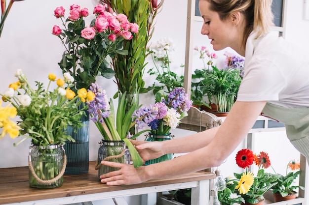 Femme concentrée, arrangeant des fleurs dans la boutique