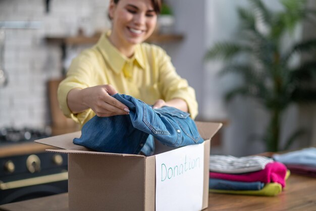 Une femme concentrée et satisfaite emballant des vêtements pour un don