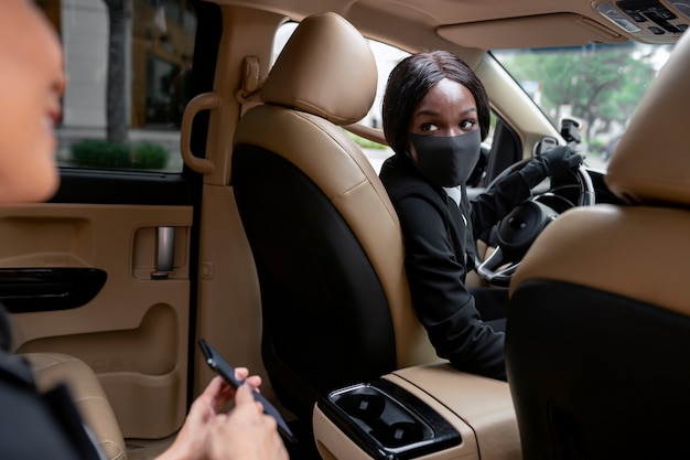 Femme conduisant son taxi avec son client sur la banquette arrière