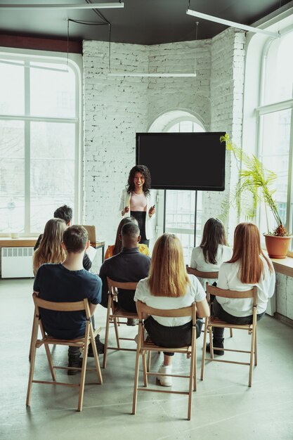 Femme conférencière afro-américaine donnant une présentation dans le hall de l'atelier universitaire