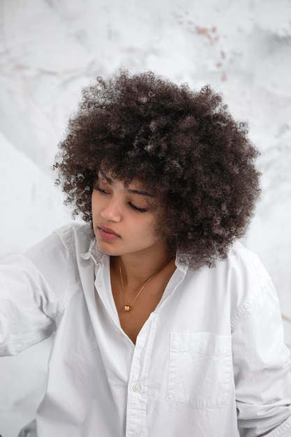 Femme confiante aux cheveux bouclés posant