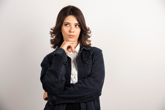 Femme confiante en veste en jean debout sur blanc.