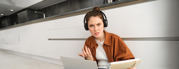 Photo gratuite une femme confuse et frustrée avec des écouteurs un étudiant ne comprend pas quelque chose en faisant ses devoirs