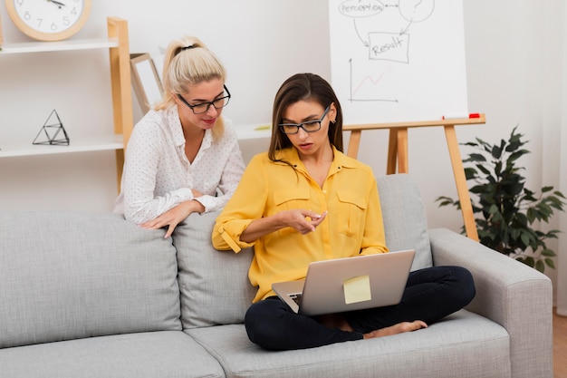 Femme confuse montrant quelque chose sur un ordinateur portable à son collègue