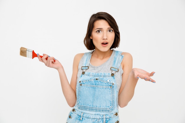 Femme confuse tenir pinceau et haussement d'épaules