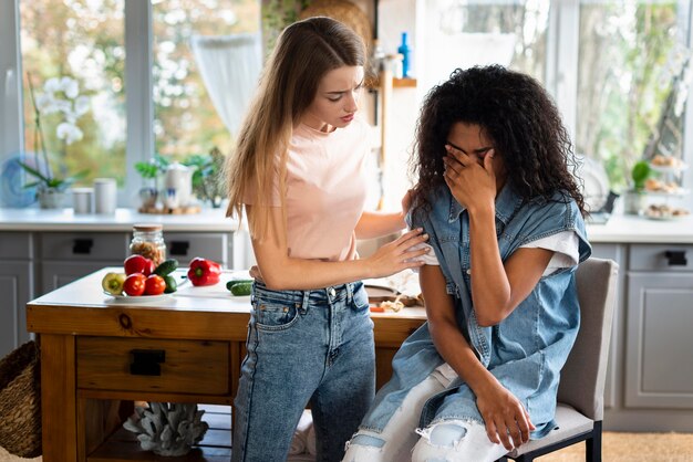 Femme consolant ses amis tristes dans la cuisine