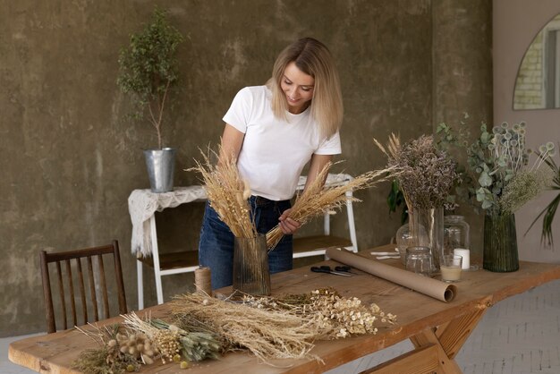 Femme construisant son propre arrangement de fleurs séchées