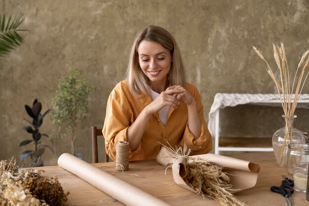 Femme construisant son propre arrangement de fleurs séchées