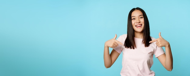 Photo gratuite une femme coréenne confiante souriante fait un visage suffisant et pointe vers elle-même l'autopromotion du bénévolat bein