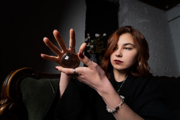 Photo gratuite femme en costume noir tenant une boule de cristal dans ses mains