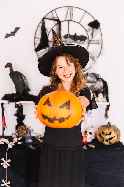 Femme En Costume De Sorcière Et Chapeau Pointu Tenant La Citrouille Et Souriant