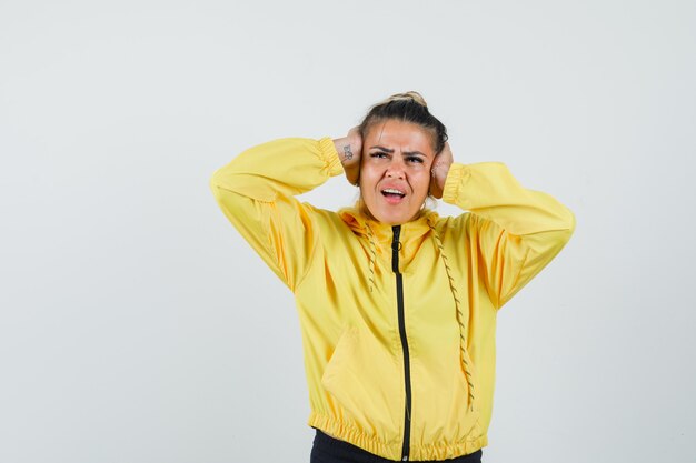 Femme en costume de sport couvrant les oreilles avec les mains et regardant irrité, vue de face.