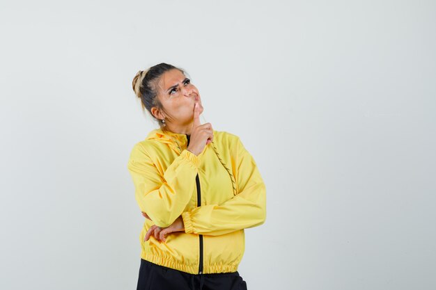 Femme en costume de sport debout dans la pensée pose et à la vue de face, hésitante.