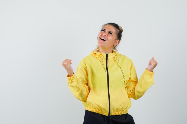 Femme en costume de sport montrant le geste du gagnant et regardant heureux, vue de face.