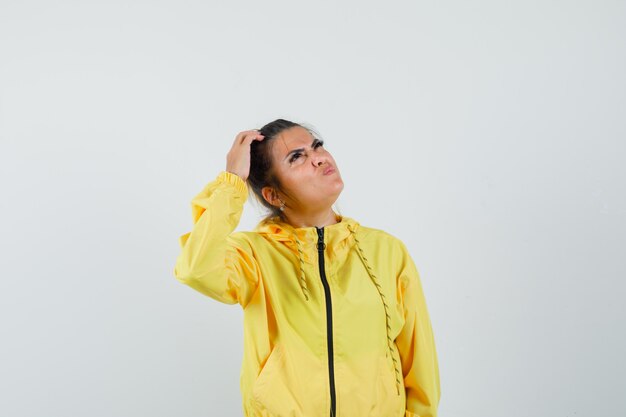 Femme en costume de sport en regardant tout en se grattant la tête et à la recherche pensive, vue de face.