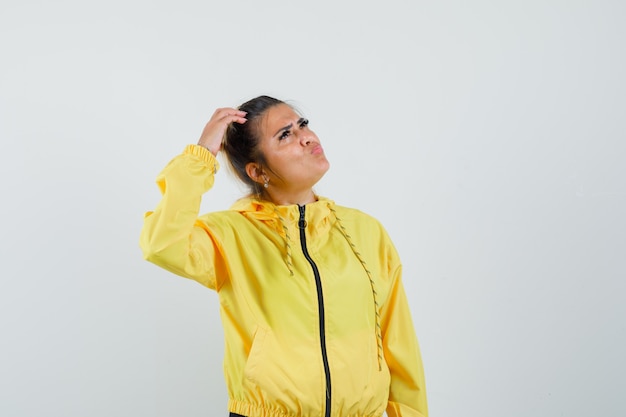 Femme en costume de sport se gratter la tête et regardant pensif, vue de face.