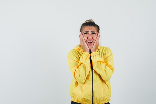 Femme en costume de sport tenant des paumes sur les joues et regardant triste, vue de face.