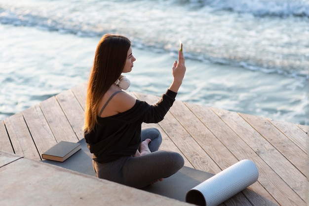 Femme sur le côté prenant une photo de la mer