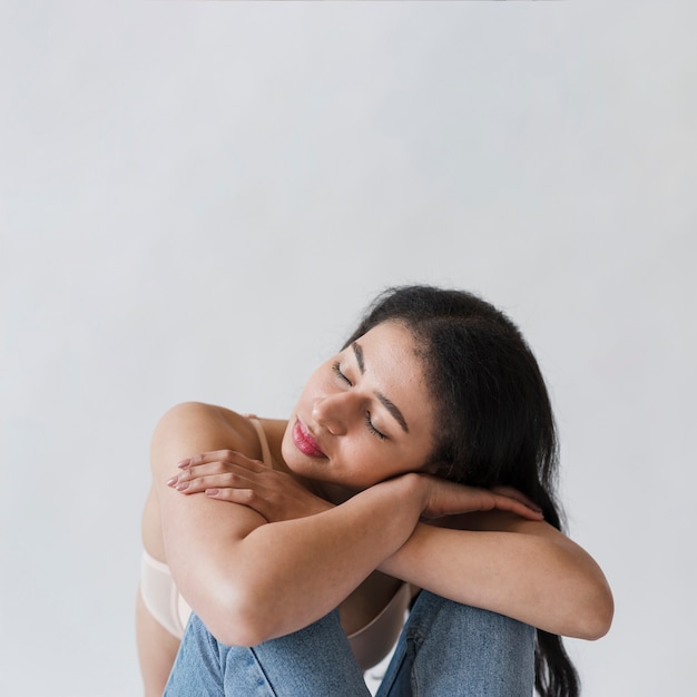 Femme couchée tête sur les bras croisés sur les genoux