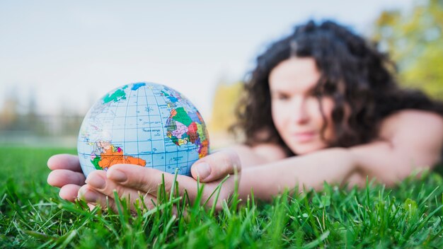 Femme, coucher herbe verte, tenant, globe, main, herbe verte