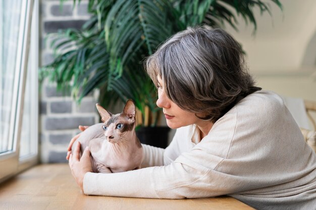 Femme de coup moyen caressant un chat sans poils