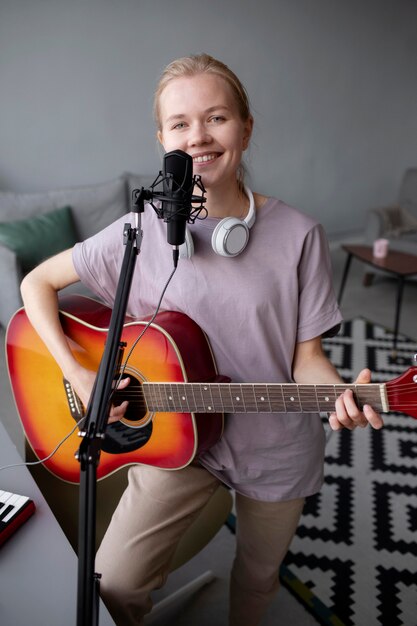 Femme de coup moyen jouant de la guitare et chantant