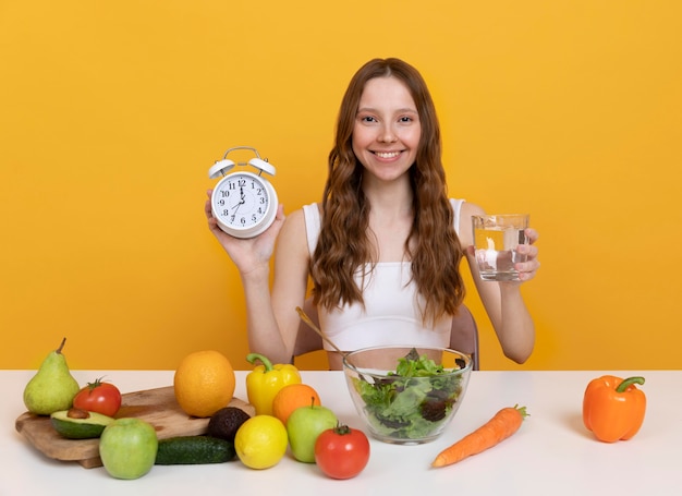 Photo gratuite femme de coup moyen avec de la nourriture et une horloge