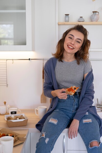 Femme de coup moyen avec une tranche de pizza