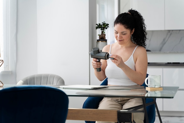 Femme à coup moyen utilisant un pistolet de massage