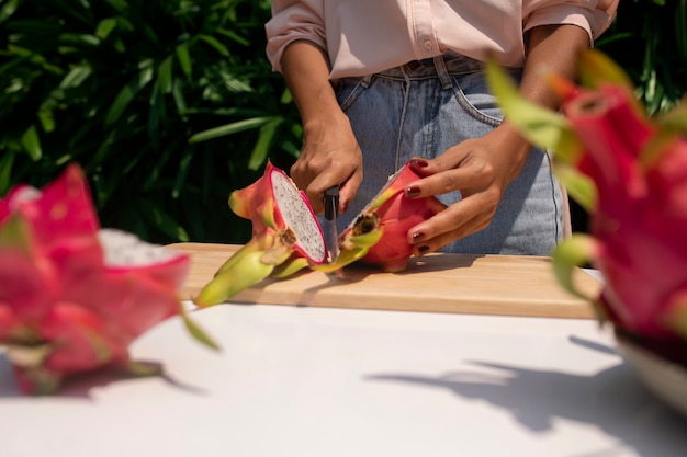 Photo gratuite femme coupant des fruits du dragon à l'extérieur