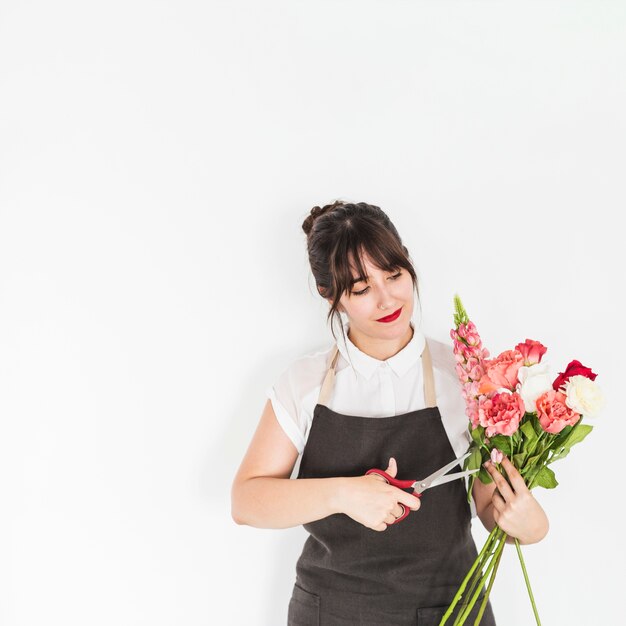 Femme coupe des brindilles de fleurs avec des ciseaux sur fond blanc