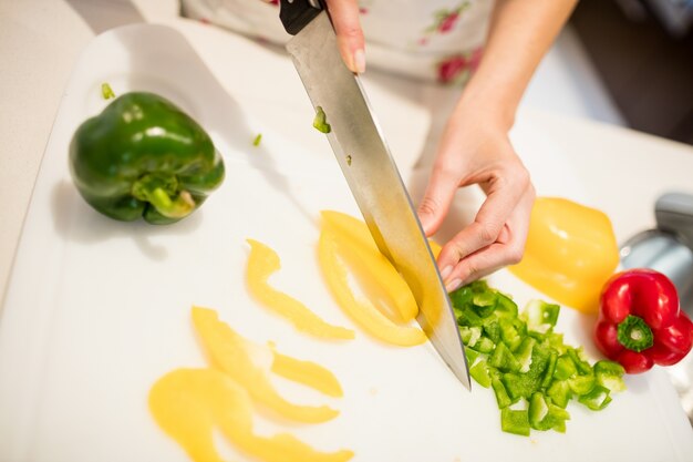 Femme coupe des légumes sur planche à découper