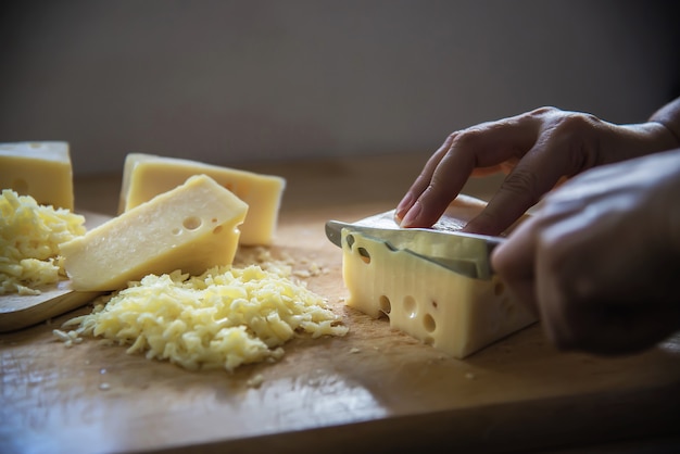 Femme coupe tranche de fromage pour cuisinier à l&#39;aide d&#39;un couteau dans la cuisine - gens faisant des aliments avec le concept de fromage