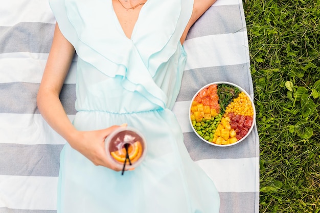 Photo gratuite femme sur une couverture avec un bol à boire et à poke