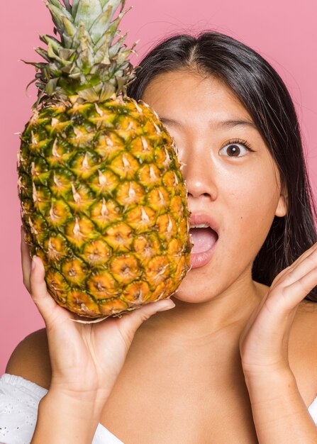 Femme couvrant son visage d'ananas en taille réelle